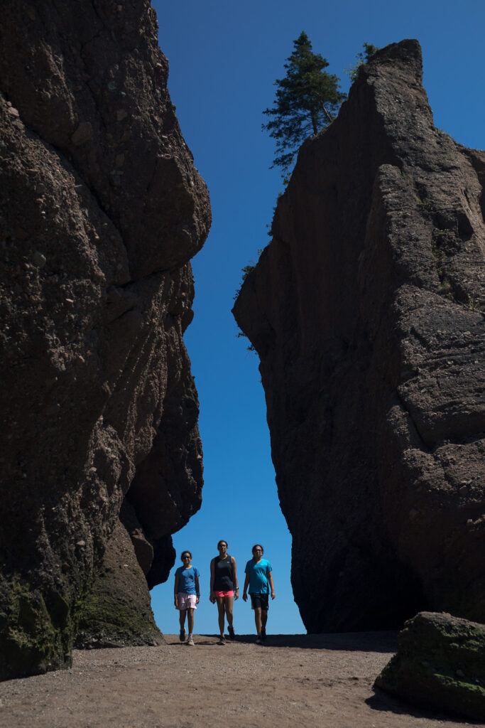 The girls walking through a gap in large rock formation.