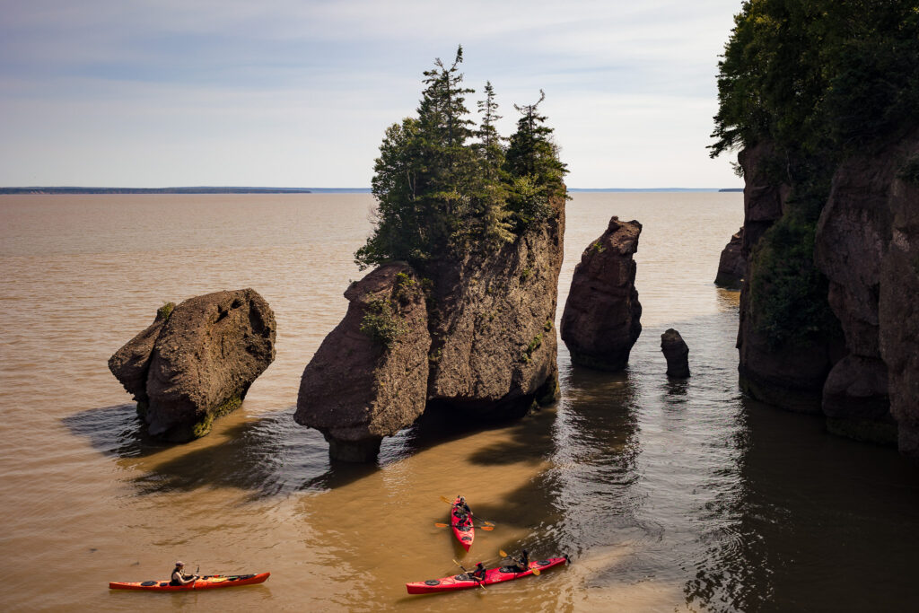 Kayaks moving through the waters around the rock formations during high tide.