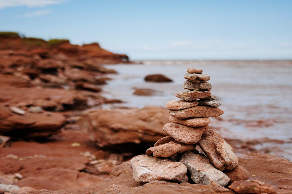 Inukshuk on red rocky sand coastline.