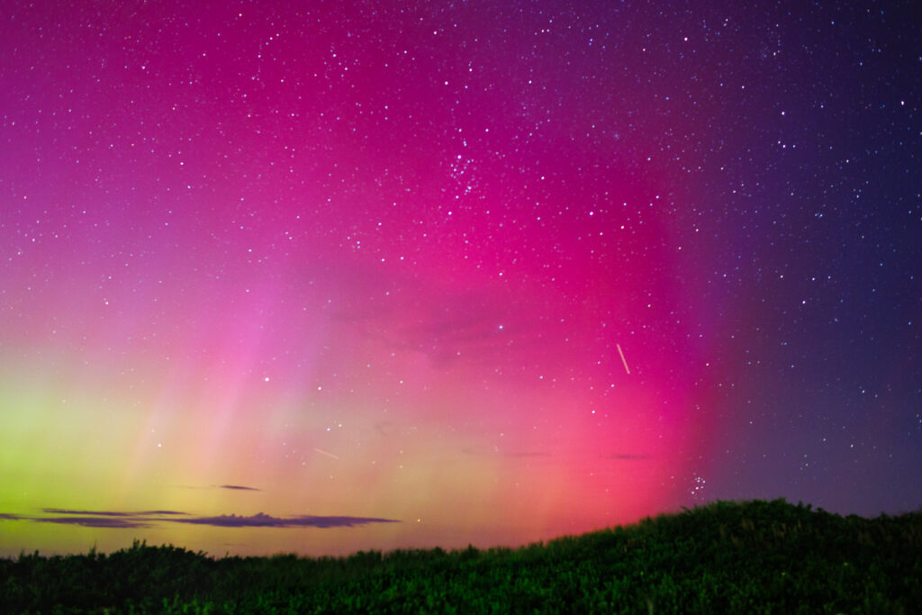 Aurora Borealis sky with pink, purple and green and two meteors.