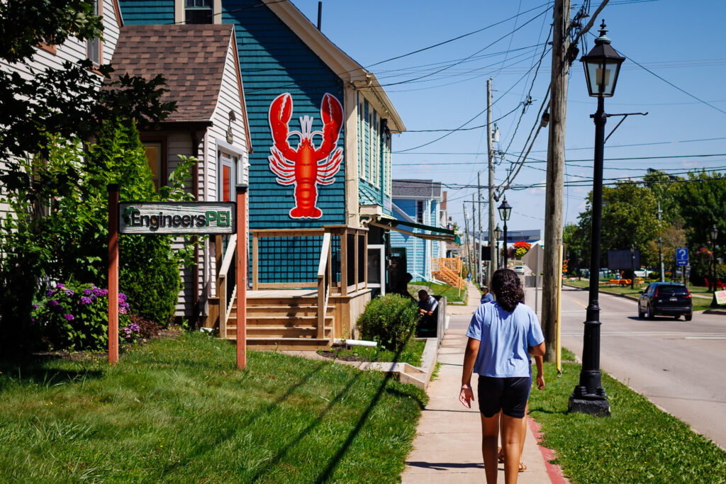 Girl walking towards blue building with a large picture of a lobster on the side. 