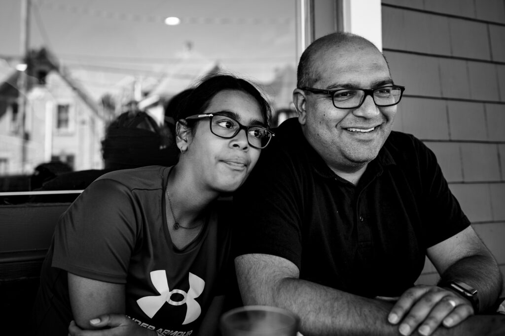Girls resting on her smiling father's shoulder.
