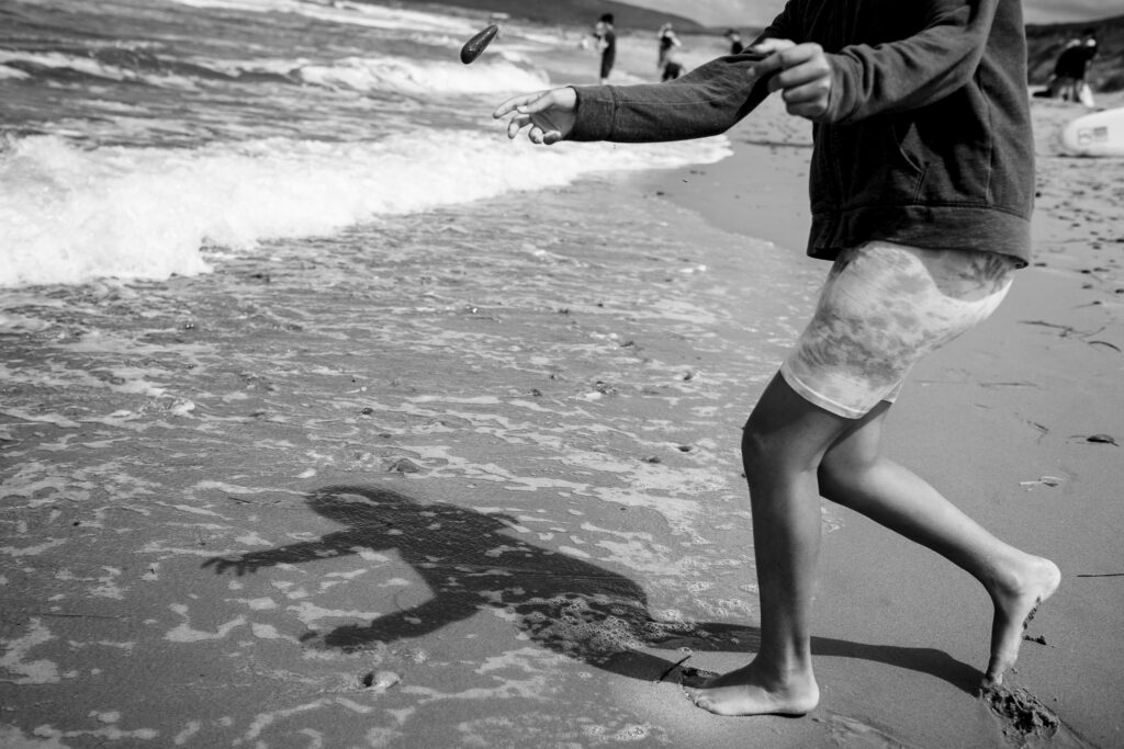 Shadow of a girl skipping rocks on a coastline. 