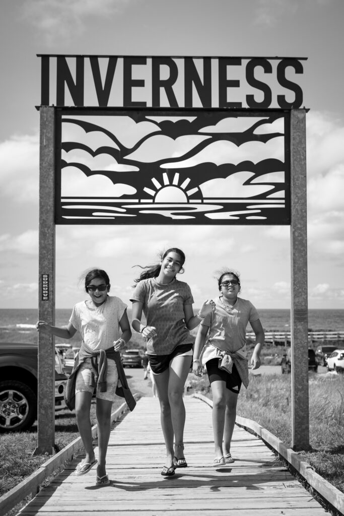 Three girls walking under a sign that says Inverness. 