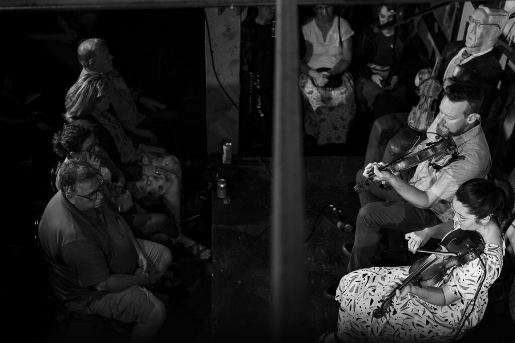Two fiddlers performing for a crowd. 