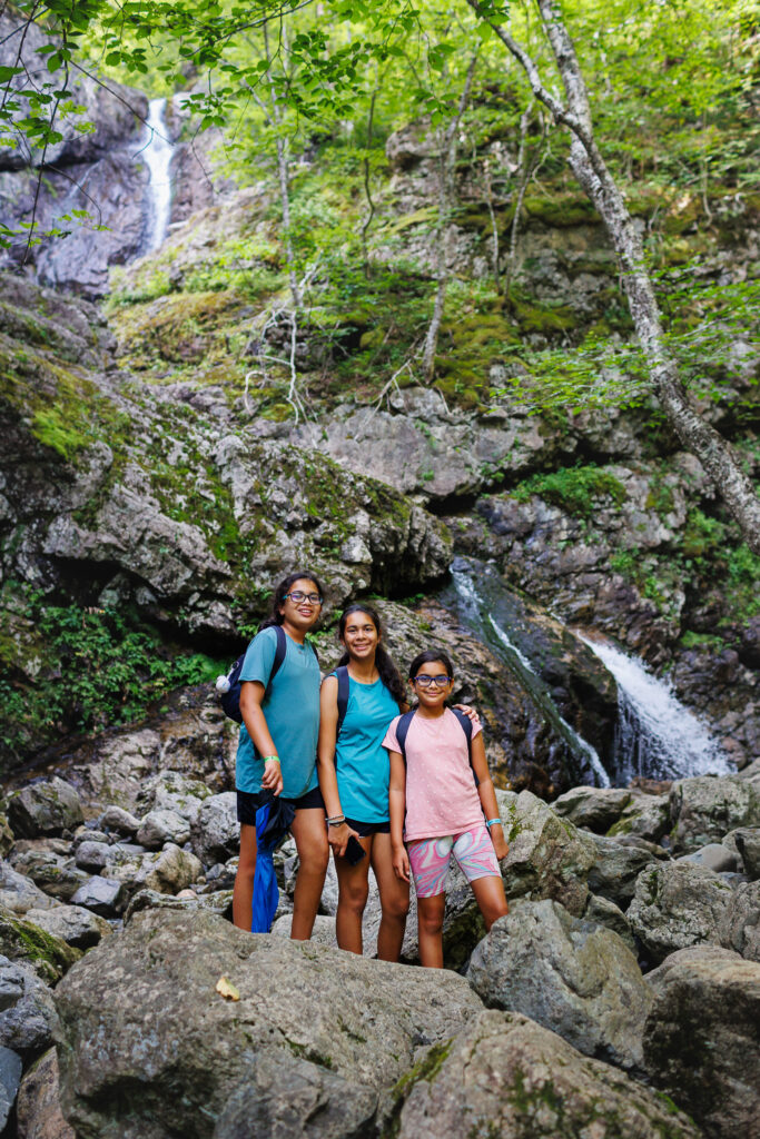 Three girls posing next to a waterfall. 
