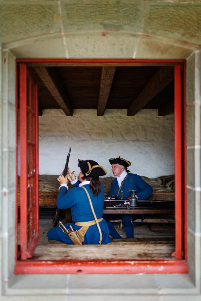Two costumed animators behind a red window. One is polishing his gun. 