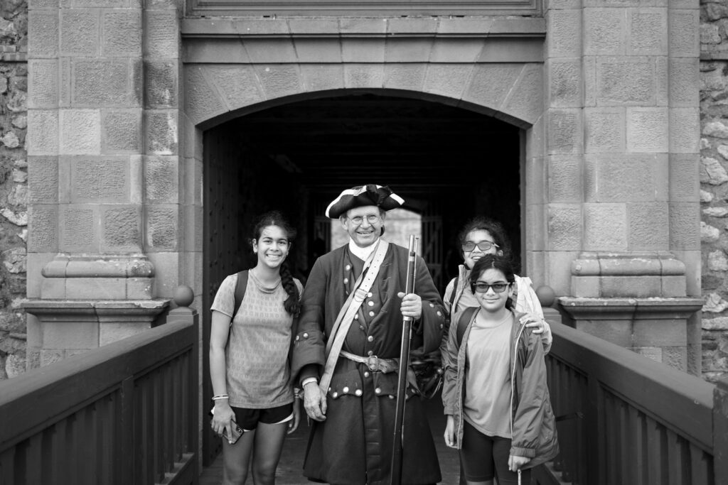 Three kids posing with a costumed animators at the Fortress of Louisbourg.