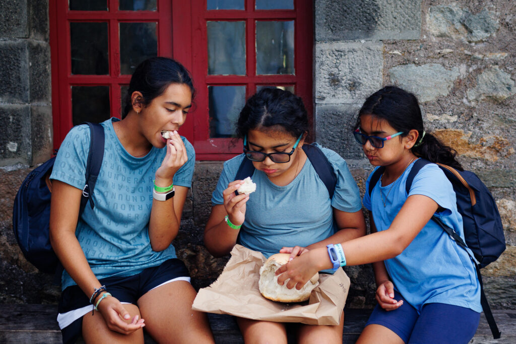 Three girls diving into a loaf soldier’s bread from the local bakery.