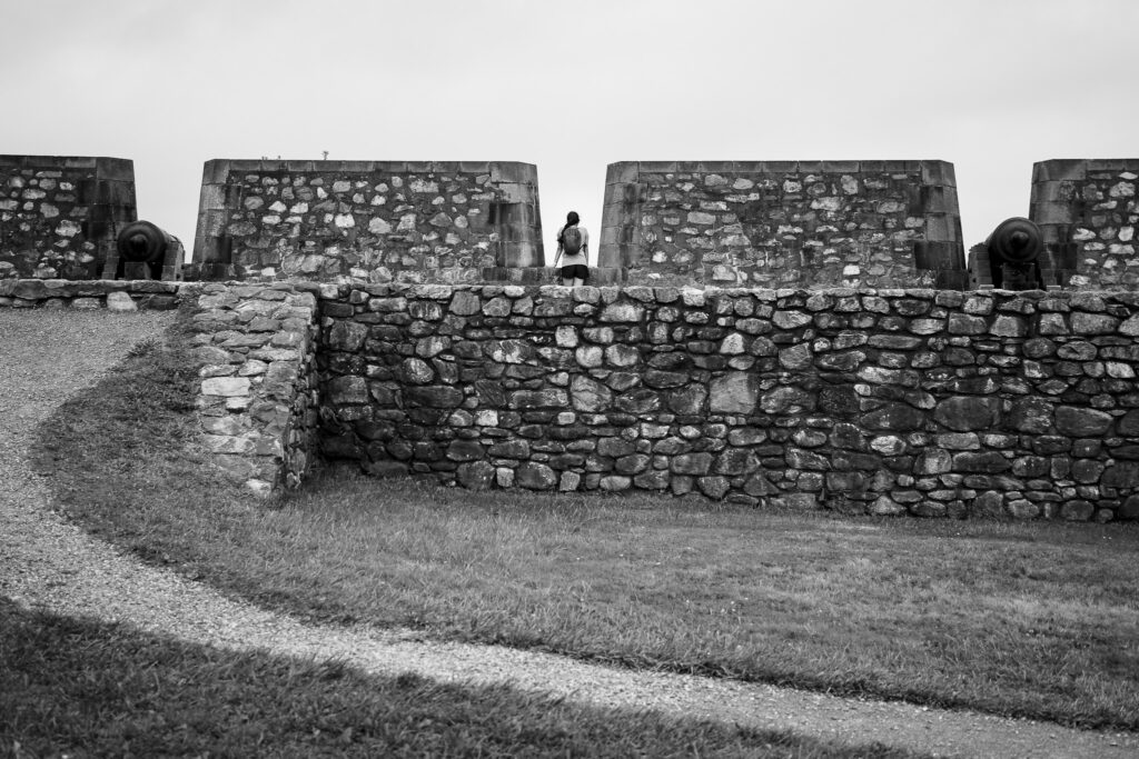 Girl looking out from opening with cannons on her right and left side. 
