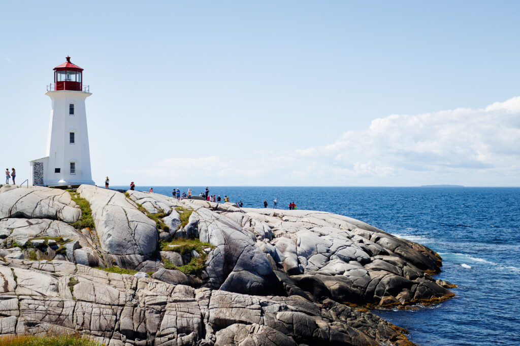 Peggy Cove's lighthouse on the rocky shores. Lots of visitors at the lighthouse. 