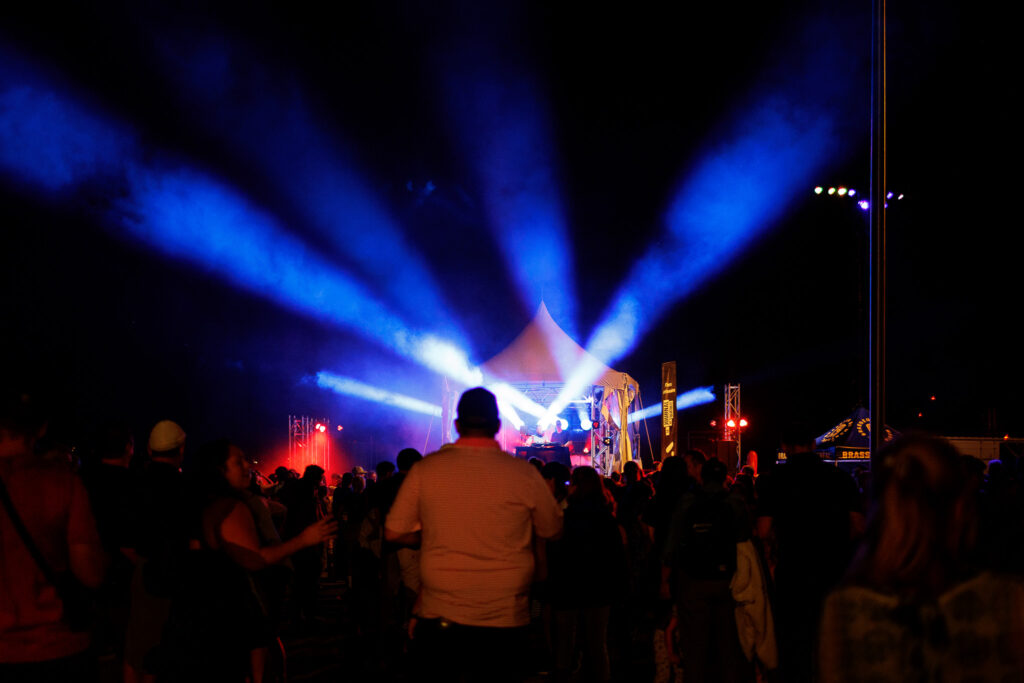 Crowd of people dancing to music and a light show. 